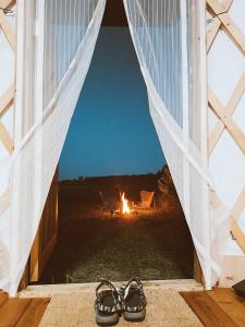 Glamping Yurt Purvs at Kleja Quiet Camping في Eikaži: زوج من الأحذية أمام نافذة فيها نار