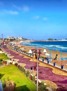una spiaggia con ombrelloni e persone che camminano sulla spiaggia di ستوديو المعموره Jerma apartments ad Alessandria d'Egitto
