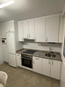a kitchen with white cabinets and a sink and a refrigerator at Amplio piso Duplex en Elorrio. in Elorrio