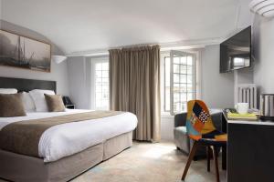 a hotel room with a bed and a desk with a chair at Hotel Le Dauphin in Honfleur