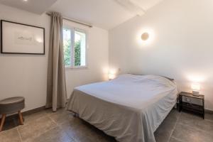 Habitación blanca con cama y ventana en Maison Le Pin, en Grimaud