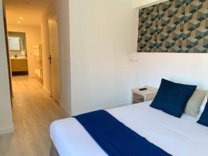 a bedroom with a bed with blue pillows and a bathroom at Hôtel de Flore in Saint-Raphaël