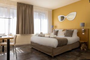 a bedroom with a large bed with a mirror on the wall at Hotel Le Dauphin in Honfleur