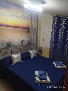 Un dormitorio con una cama azul con una pintura en la pared en Splendido Attico, en Roseto Capo Spulico