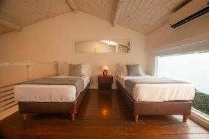two beds in a room with a window at Serena Buzios in Búzios
