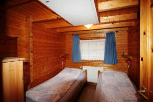 een slaapkamer met een bed en een raam met blauwe gordijnen bij Diekkieker - a90262 in Niederstrich