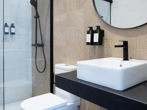 a bathroom with a sink and a shower and a mirror at Meraki Suites in Astorga