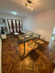 a room with a glass table and chairs on a wooden floor at Departamento Necochea in Rosario