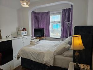 a bedroom with a bed and a window with purple curtains at Lovely Rooms London in London