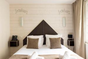a bedroom with a bed with white sheets and pillows at Hotel Le Dauphin in Honfleur