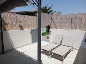 zwei Stühle auf einer Terrasse neben einem Zaun in der Unterkunft Sabbia d'oro in Santa Maria Del Focallo