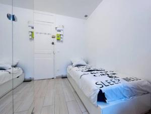 a white bedroom with a bed and a mirror at Sur les Toits de Paris in Paris