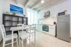 una cucina con tavolo, sedie e frigorifero di Appartamenti La perla a Carloforte