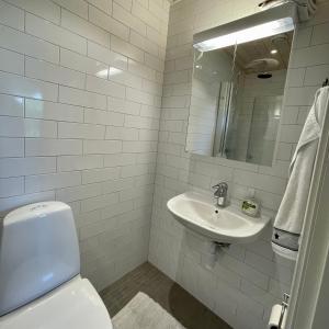 a white bathroom with a toilet and a sink at Studion in Falun