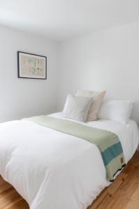 Cama blanca con sábanas y almohadas blancas en Le Boulevard par Maison Dudley en Lac-Mégantic