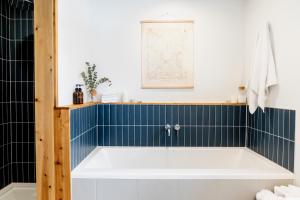a bath tub in a bathroom with blue tiles at Le Boulevard par Maison Dudley in Lac-Mégantic