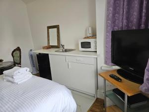 1 dormitorio con 1 cama, TV y microondas en Lovely Rooms London en Londres