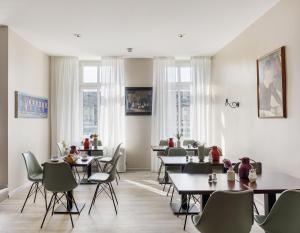 ein Esszimmer mit Tischen, Stühlen und Fenstern in der Unterkunft Hotel Nova in Berlin
