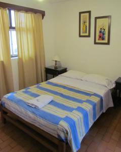 a bedroom with a bed with a blue and white blanket at Huanchaco Hostal in Huanchaco