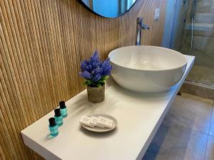 baño con lavabo blanco y jarrón de flores púrpuras en Luna Nuova Suites, en Nápoles