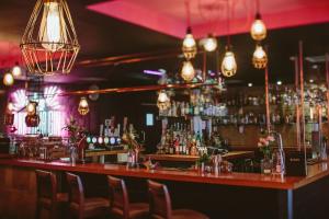 a bar in a restaurant with chairs and lights at Glasgow Grosvenor Hotel in Glasgow