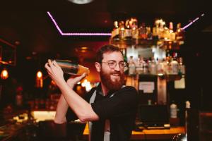 a man standing at a bar holding a beer at Glasgow Grosvenor Hotel in Glasgow