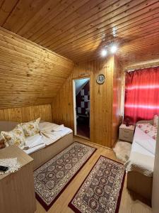 a room with two beds in a wooden room at Pensiunea Valea Frumoasei in Şugag