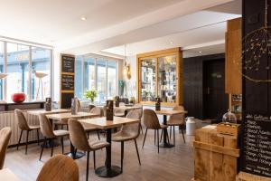 a restaurant with wooden tables and chairs and windows at Hotel Le Dauphin in Honfleur