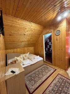 Zimmer mit einem Bett in einem Holzzimmer in der Unterkunft Pensiunea Valea Frumoasei in Şugag
