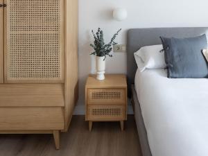 Un dormitorio con una cama y un jarrón en una mesita de noche en Meraki Suites, en Astorga
