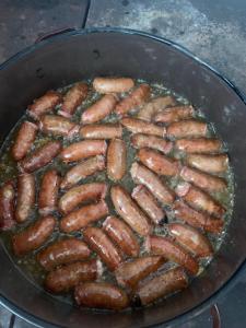 a bunch of sausages cooking in a pan at Pensiunea Valea Frumoasei in Şugag