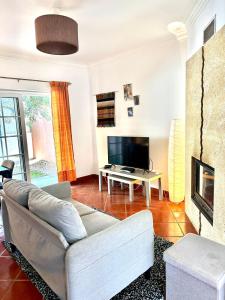uma sala de estar com um sofá e uma televisão em casa de praia em Charneca