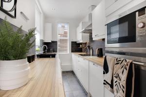 uma cozinha com armários brancos e um vaso de plantas em Terrace View Home in South Shields, Sleeps 7 em South Shields