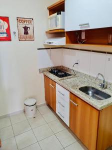 eine kleine Küche mit einer Spüle und einer Mikrowelle in der Unterkunft Flat Pertinho do Hot Park (200m)! Aconchegante! in Rio Quente