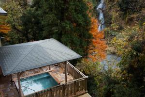 a gazebo with a waterfall in the background at Yamanaka Onsen Kissho Yamanaka in Kaga