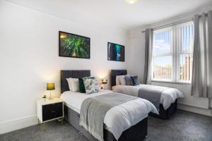 Duas camas num quarto com paredes brancas e janelas em Spacious 3-Bed Home in South Shields, Sleeps 8 em South Shields