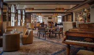 a restaurant with a piano and tables and chairs at Glasgow Grosvenor Hotel in Glasgow
