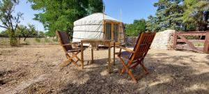 twee stoelen en een tafel naast een yurt bij Agriturismo Poggio Ferrata in Ruvo di Puglia