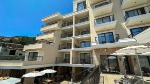 a large building with tables and umbrellas in front of it at Hotel Pima Budva in Budva