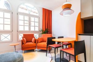 ein Wohnzimmer mit orangefarbenen Stühlen und einem Tisch in der Unterkunft Apartamentos El Reloj in Luanco