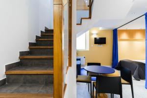 eine Treppe in einem Wohnzimmer mit einem Tisch und Stühlen in der Unterkunft Apartamentos El Reloj in Luanco