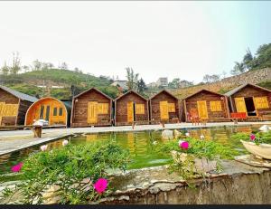 a group of wooden huts with a pool of water at Thạch Gia Trang Sapa in Sapa
