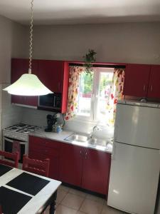 a kitchen with red cabinets and a white refrigerator at Rouvas Beach House in Sidari +23 photos