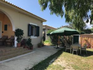 a patio with a table and an umbrella at Rouvas Beach House in Sidari