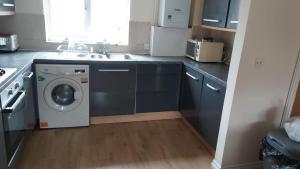 a kitchen with a washing machine and a sink at Lovely 2 Bedroom Family Holiday Home in Thamesmead