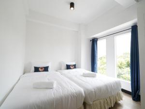 una camera bianca con un grande letto con due cuscini di RoomQuest IT Square Don Mueang Airport a Bangkok