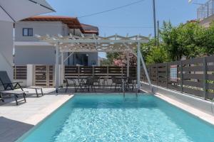 a swimming pool with a pergola and a table and chairs at Sunshine Rooms and Suites in Nea Vrasna
