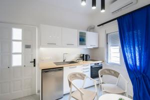 a kitchen with white cabinets and a table and chairs at Georgia apartments in town in Skiathos Town