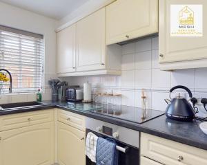 a kitchen with white cabinets and a tea kettle on the stove at Ashford Home with 3 Bedrooms, Ideal for Contractors by Mesh Accommodation in Ashford +11 photos