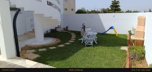 a small backyard with a table and chairs on the grass at Dar Lebharr Kélibia in Kelibia